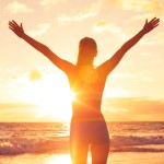 woman on sunny beach holding arms up